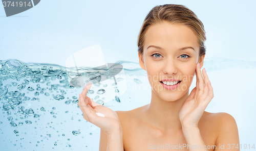 Image of smiling young woman applying cream to her face