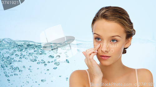 Image of young woman applying cream to her face