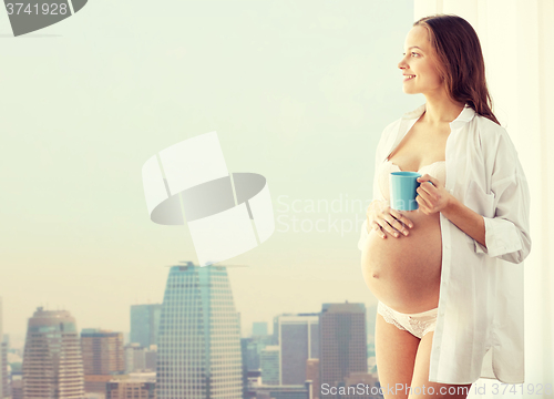 Image of happy pregnant woman with cup drinking tea at home