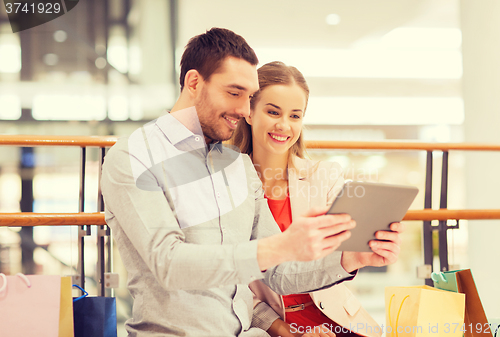 Image of couple with tablet pc and shopping bags in mall