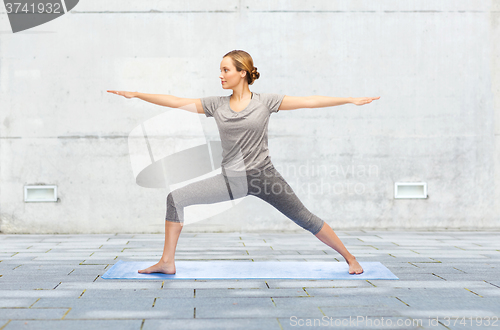 Image of woman making yoga warrior pose on mat