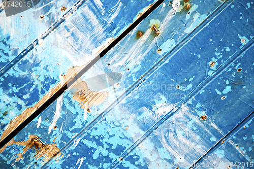 Image of stripped paint in the blue  and rusty nail