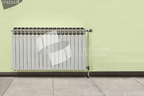 Image of Gray radiator on a yellow wall