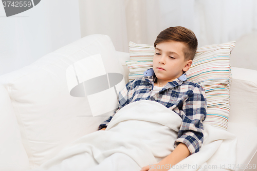 Image of ill boy with flu lying in bed at home