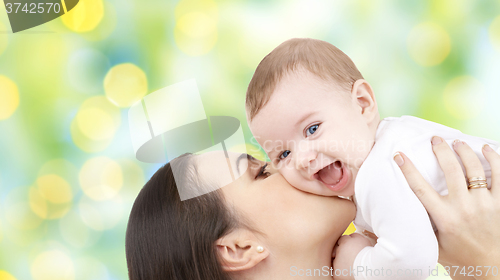 Image of happy mother kissing her baby over green lights