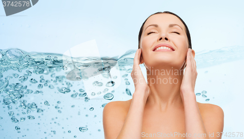 Image of smiling young woman cleaning her face over water