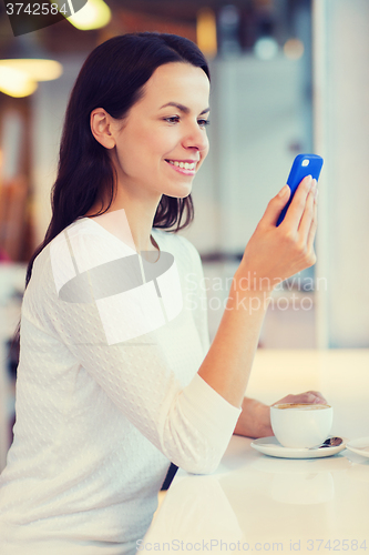 Image of smiling woman with smartphone and coffee at cafe