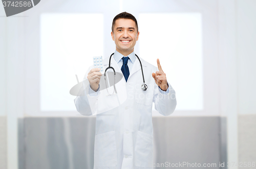 Image of smiling male doctor in white coat with pills