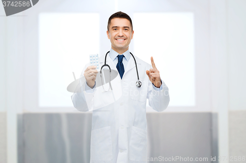 Image of smiling male doctor in white coat with pills