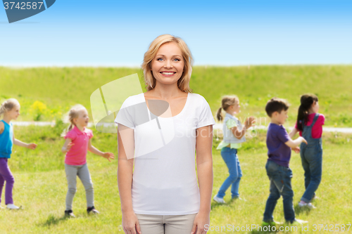 Image of smiling woman over group of little kids outdoors