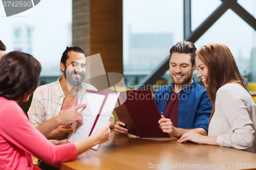 Image of smiling friends discussing menu at restaurant
