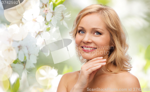 Image of smiling woman with bare shoulders touching face