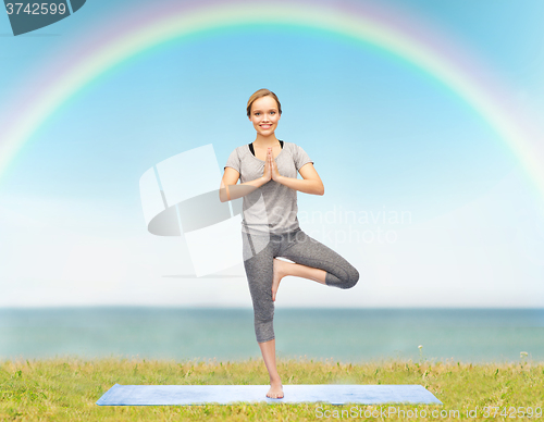 Image of woman making yoga in tree pose on mat