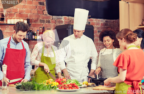 Image of happy friends and chef cook cooking in kitchen