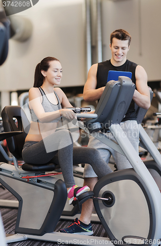 Image of happy woman with trainer on exercise bike in gym