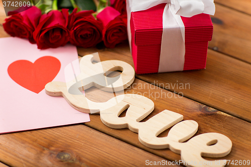 Image of close up of gift box, red roses and greeting card