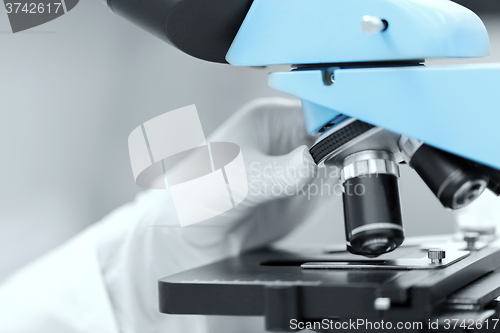 Image of close up of scientist hand setting microscope