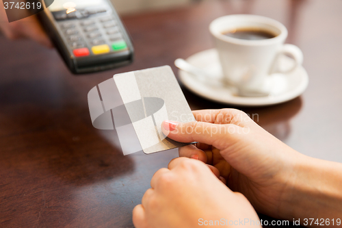 Image of close up of hands with credit card reader at cafe