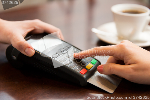 Image of close up of hands with credit card reader at cafe