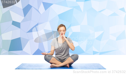 Image of woman making yoga meditation in lotus pose on mat