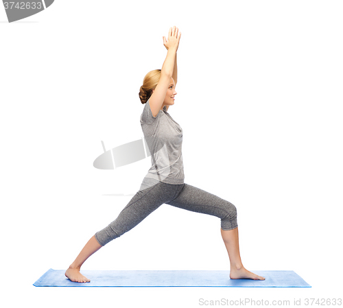 Image of woman making yoga warrior pose on mat