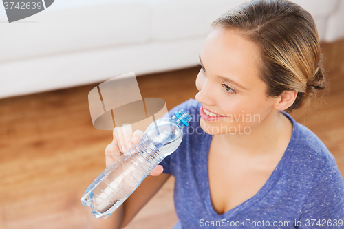 Image of happy woman with water bottle at home