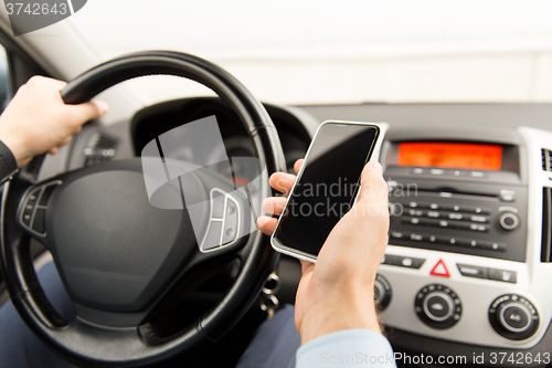 Image of close up of man hand with smartphone driving car