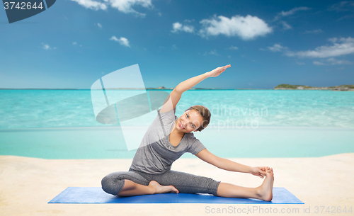 Image of happy woman making yoga and stretching on beach 