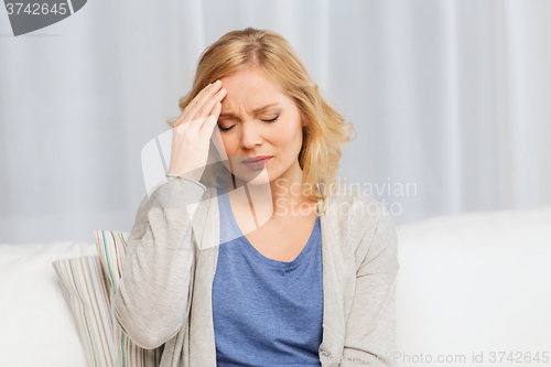 Image of unhappy woman suffering from headache at home