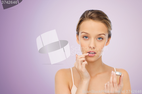 Image of young woman applying lip balm to her lips