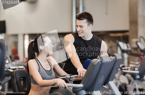 Image of happy woman with trainer on exercise bike in gym