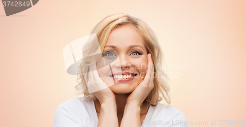 Image of smiling woman in white t-shirt touching her face
