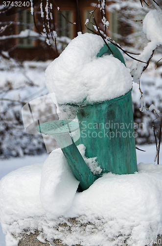 Image of one old watering can with snow