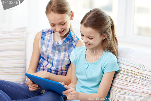 Image of happy girls with tablet pc sitting on sofa at home