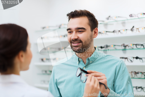 Image of optician showing glasses to man at optics store