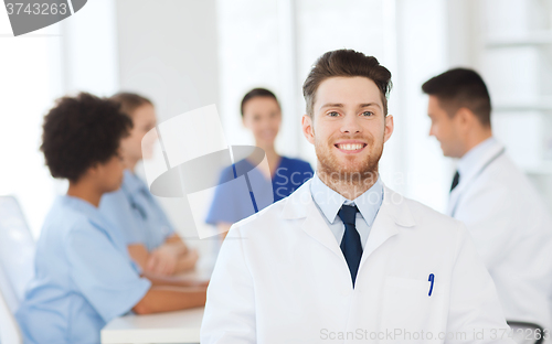 Image of happy doctor over group of medics at hospital