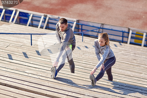 Image of couple stretching leg on stands of stadium