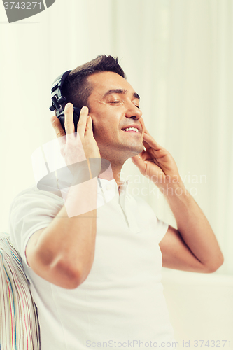 Image of happy man in headphones listening to music at home