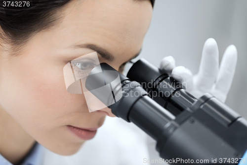 Image of close up of scientist looking to microscope in lab