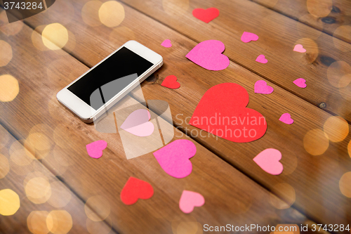 Image of close up of smartphone and hearts on wood