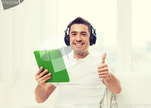 Image of smiling man with tablet pc and headphones at home