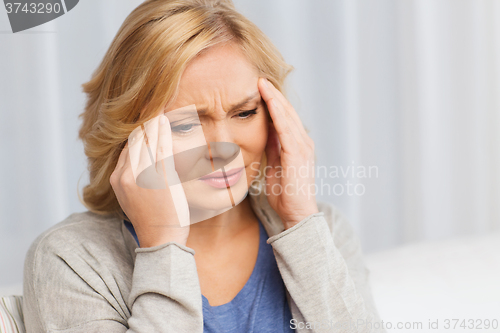 Image of unhappy woman suffering from headache at home