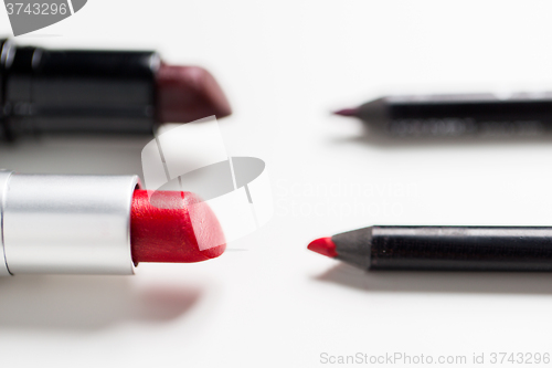 Image of close up of two open lipsticks and lip pencils