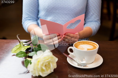 Image of close up of woman reading greeting card and coffee