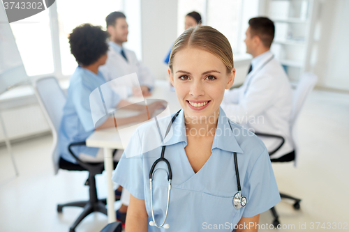 Image of happy doctor over group of medics at hospital