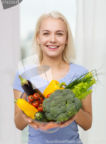 Image of smiling young woman with vegetables at home