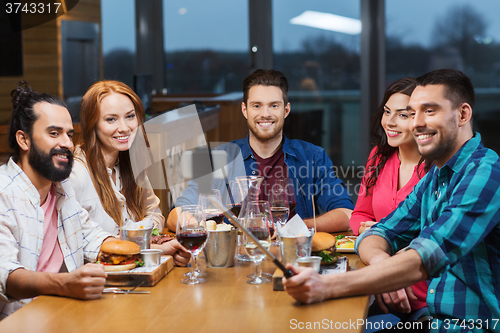 Image of friends taking selfie by smartphone at restaurant