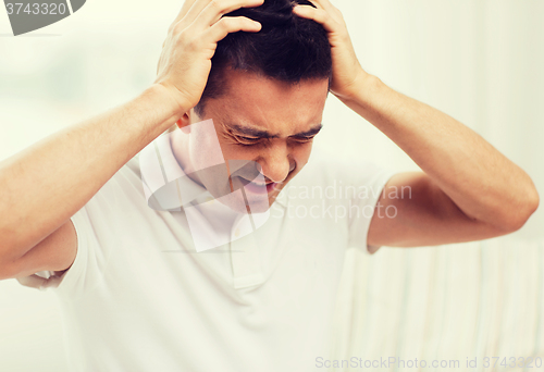 Image of unhappy man suffering from head ache at home