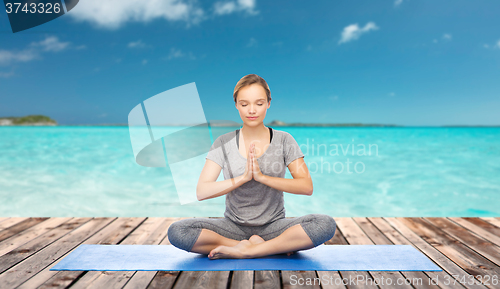 Image of woman making yoga meditation in lotus pose on mat