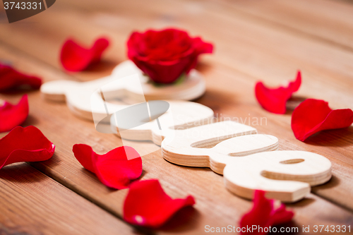 Image of close up of word love cutout with red rose on wood